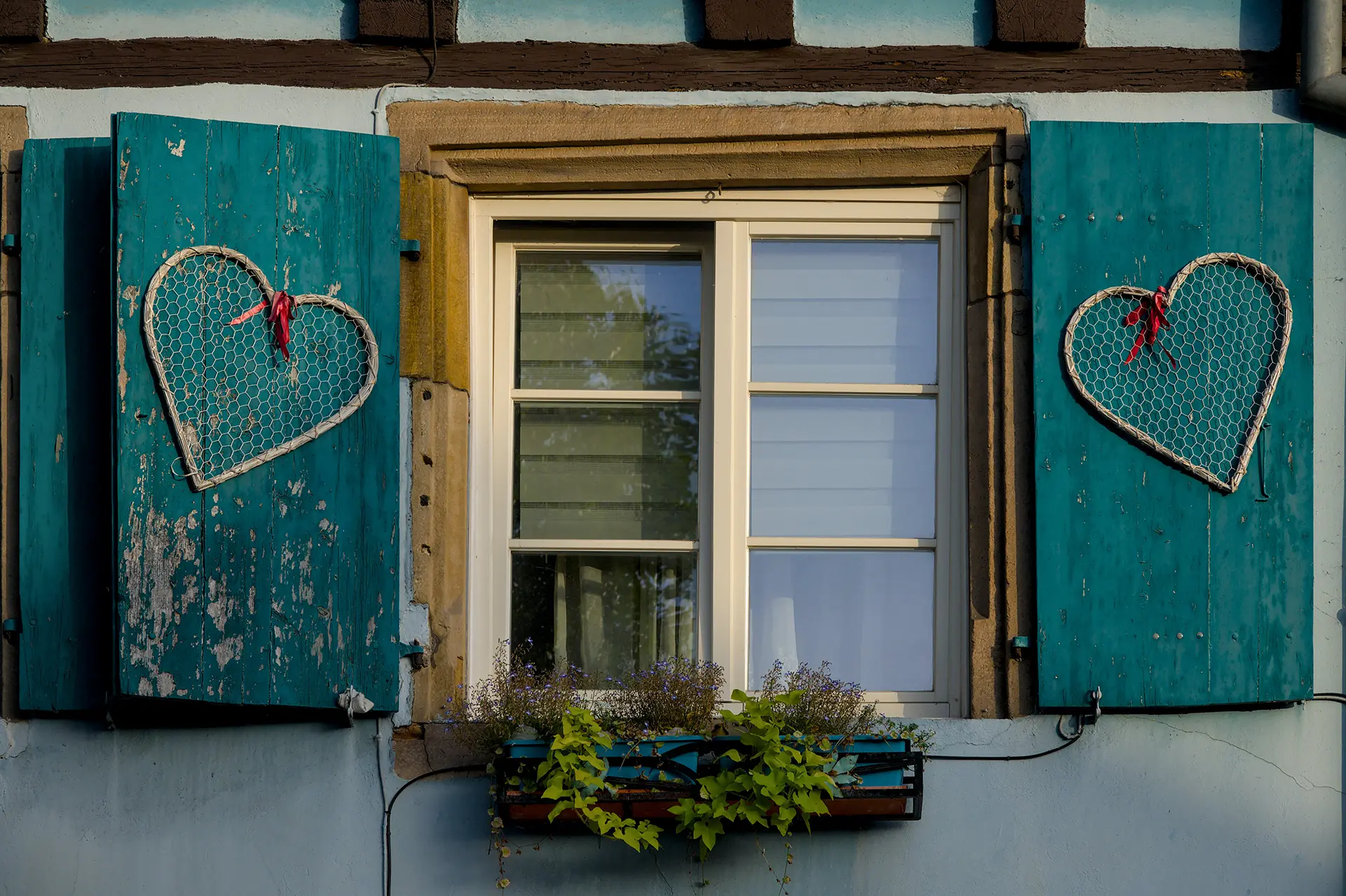 Window on home with wood shutters and heart shaped holiday decor