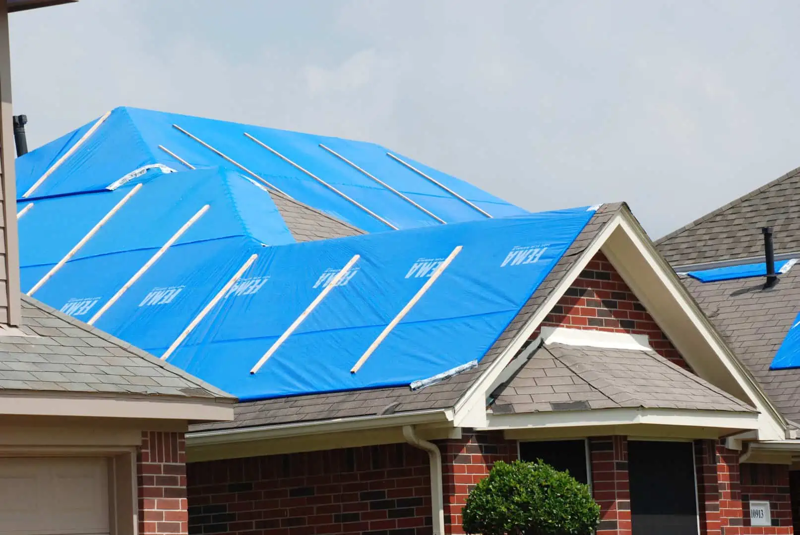 Home with blue tarp covering storm damage