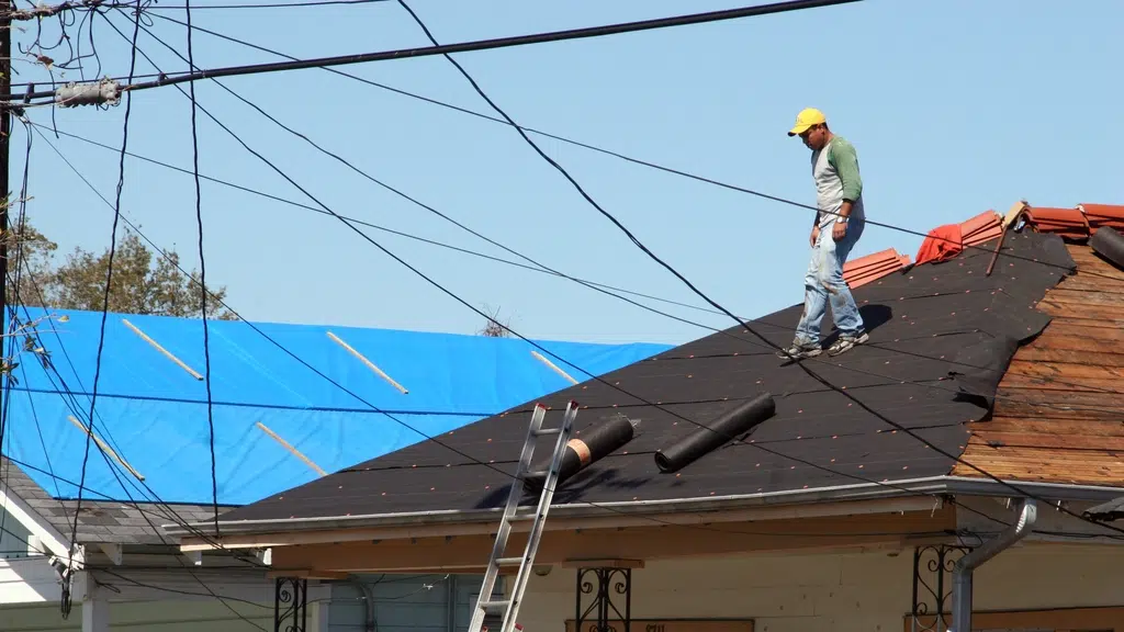 worker standing on half completed shingle roof