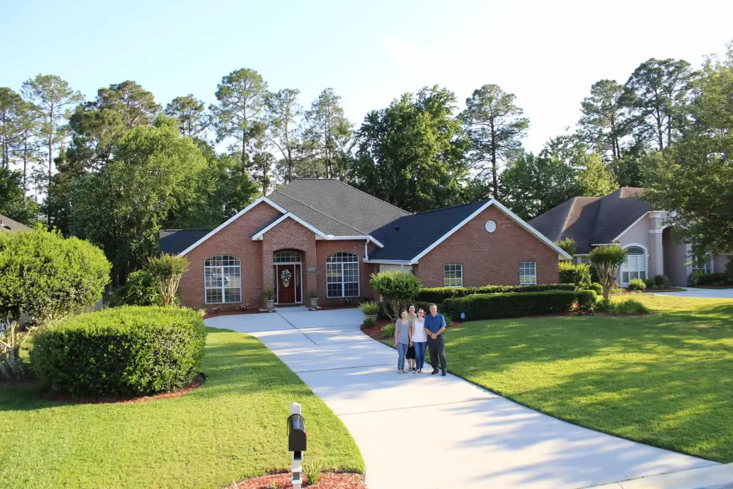 Couple hugging in front of single story home