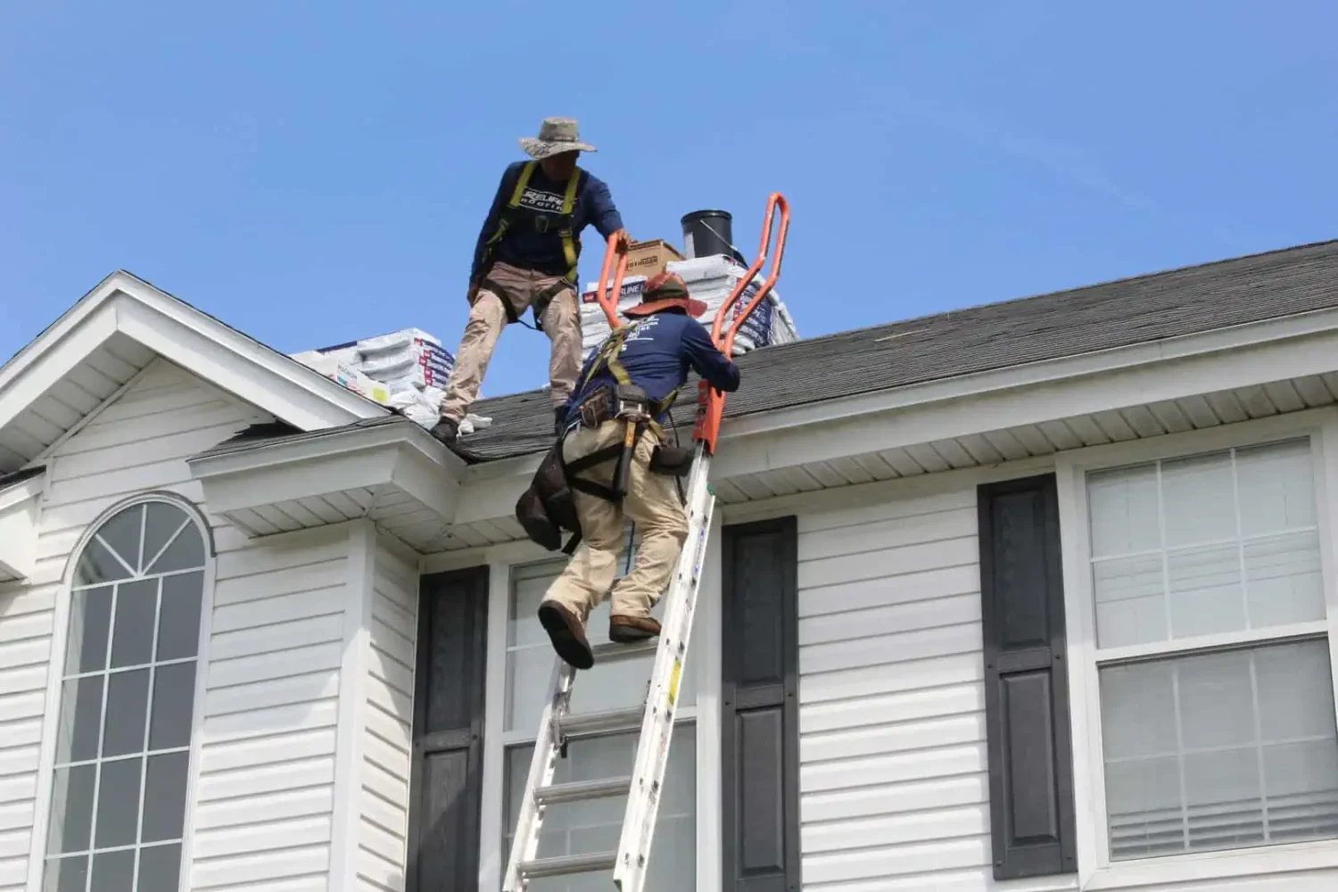 Workers climbing ladder on to a roof