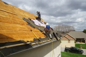 Workers applying shingles to roof