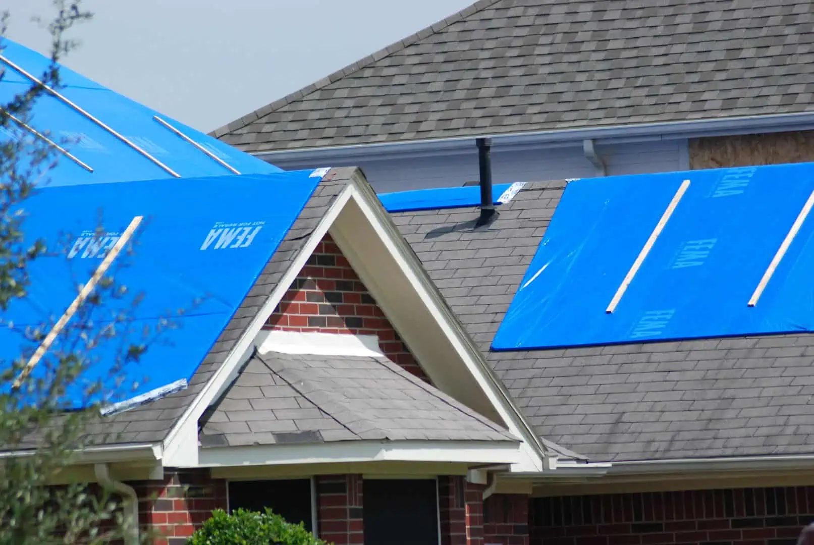 Roofs with storm damage covered with blue tarps