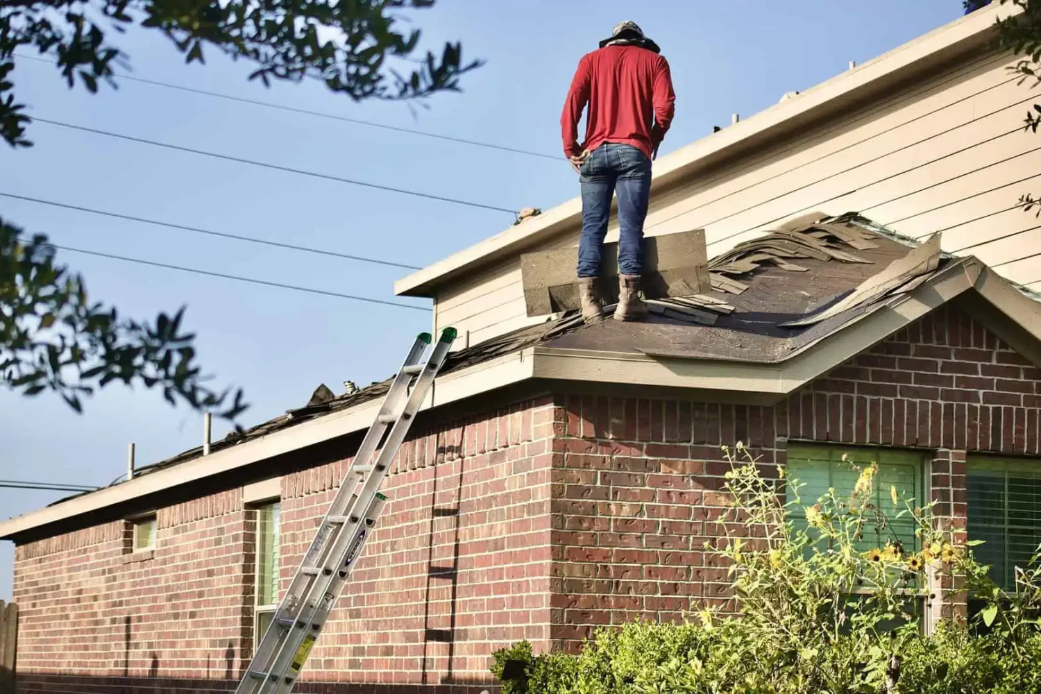 worker standing on roof next to ladder