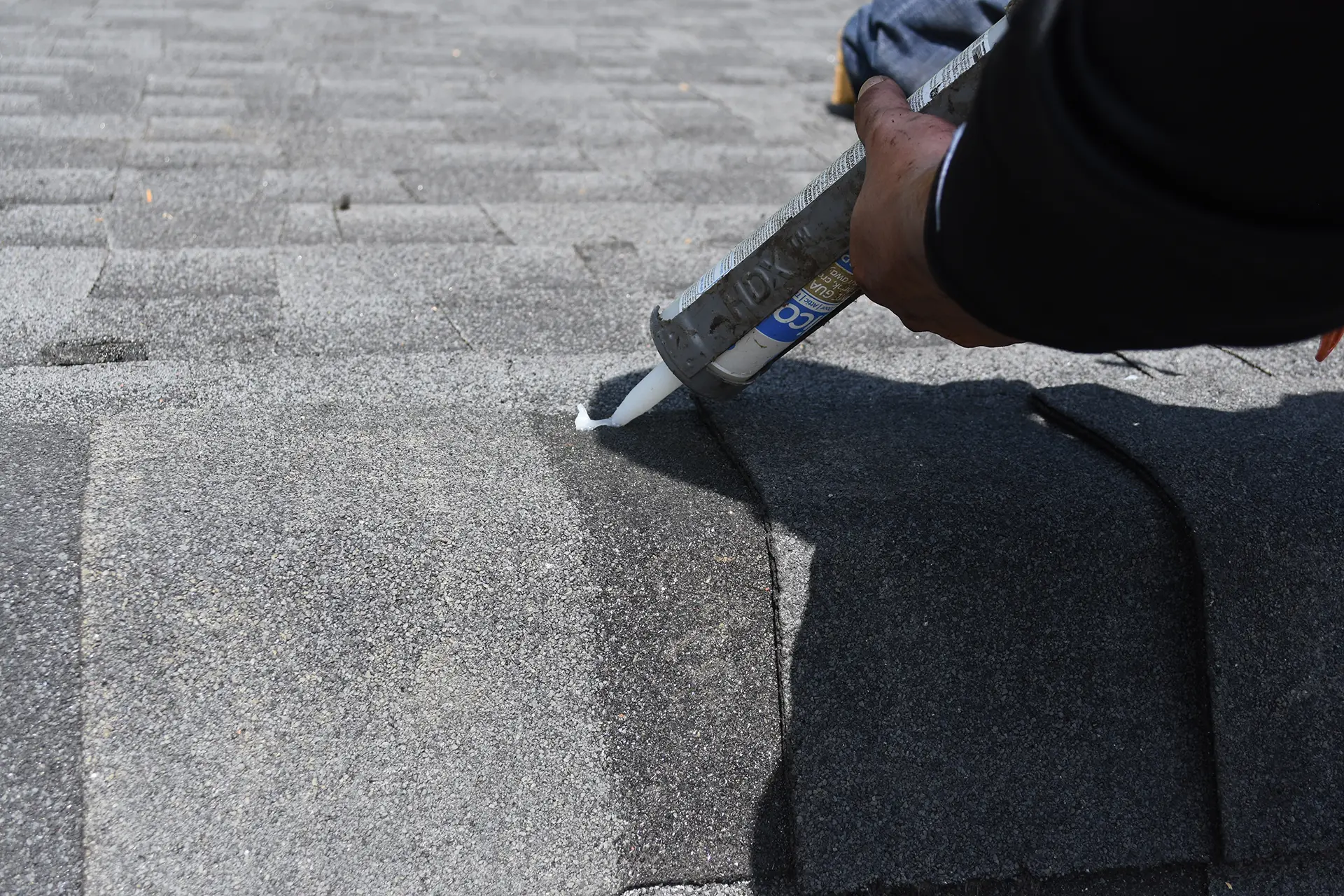 Roofer applying sealant to shingles